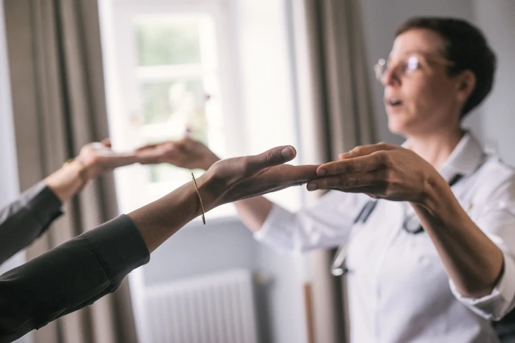 Frau h&auml;lt die H&auml;nde einer Patientin w&auml;hrend einer Therapie