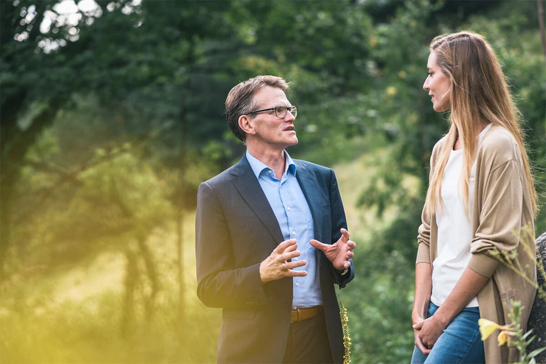 Mann in Anzug spricht mit einer Frau, drau&szlig;en in der Natur